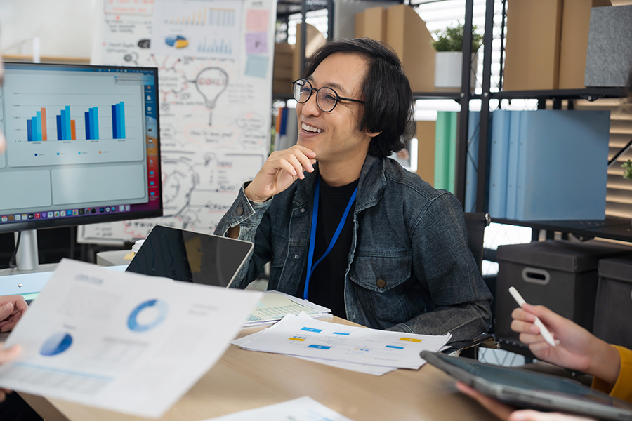 Smiling man reviews charts and diagrams in an office setting.