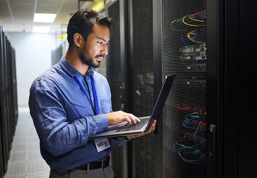 IT professional checking a laptop in a server room.