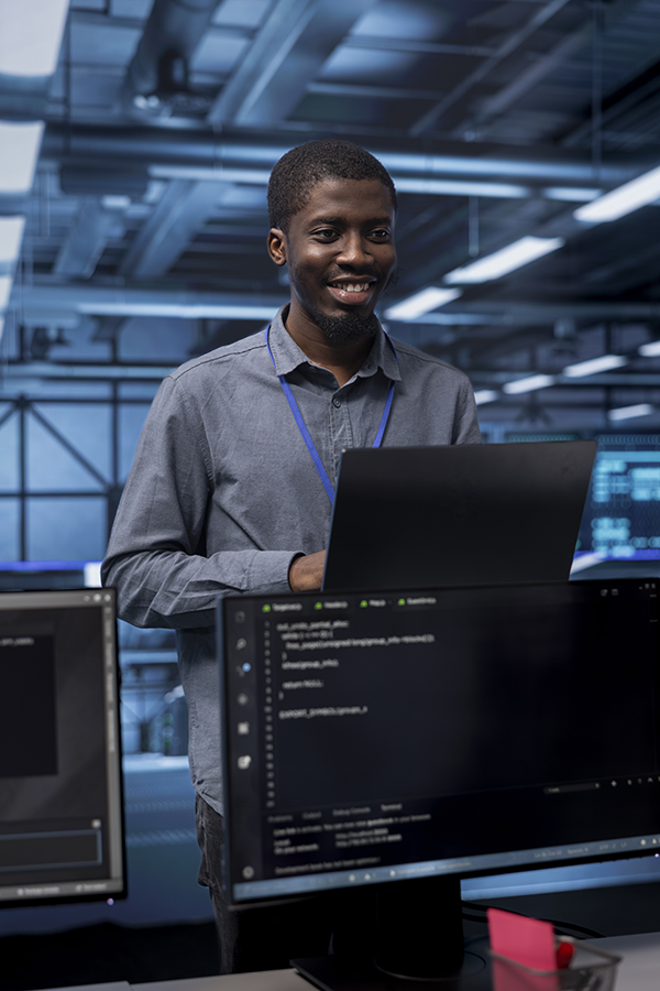 Man smiling while working on a laptop in a sleek tech-focused environment.