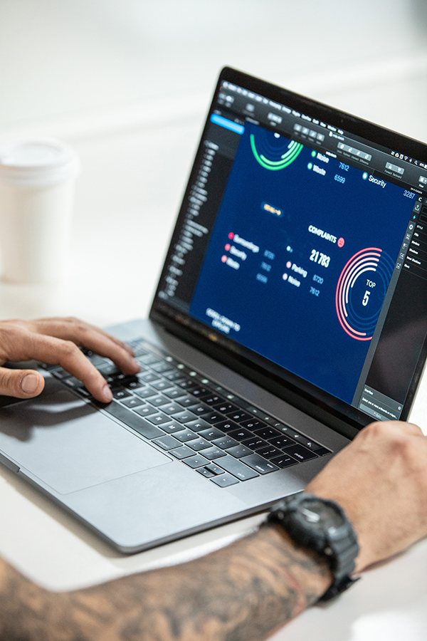 Hands using a laptop showing a data dashboard with charts and visual metrics.